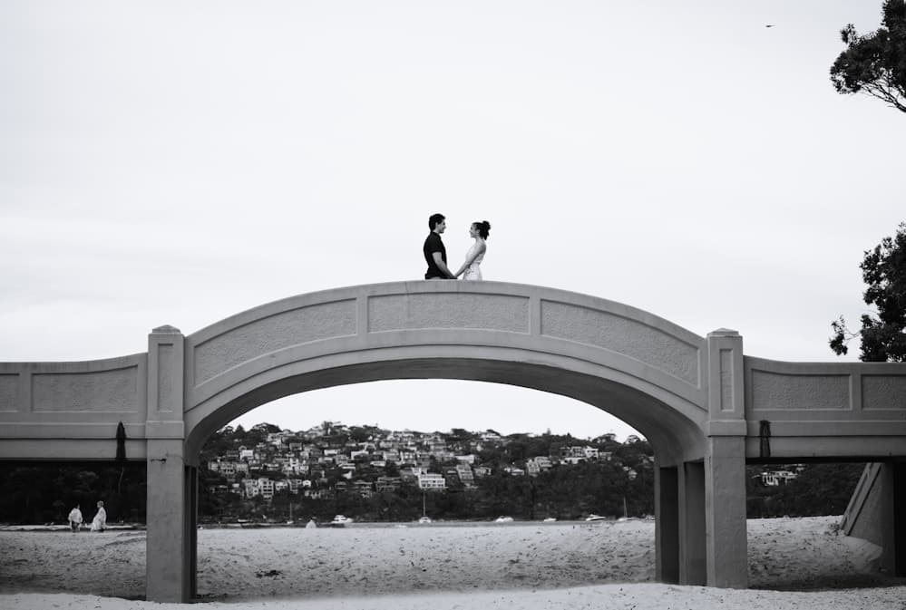 Black and white engagement photo of a couple on a bridge