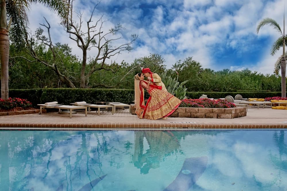 Bride and groom by a pool with palm trees